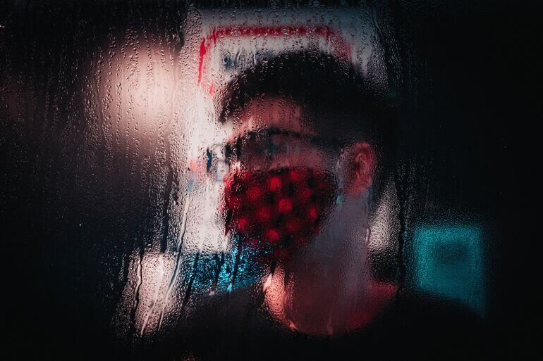 Person behind a steamed up window wearing a face mask - Cookiebot